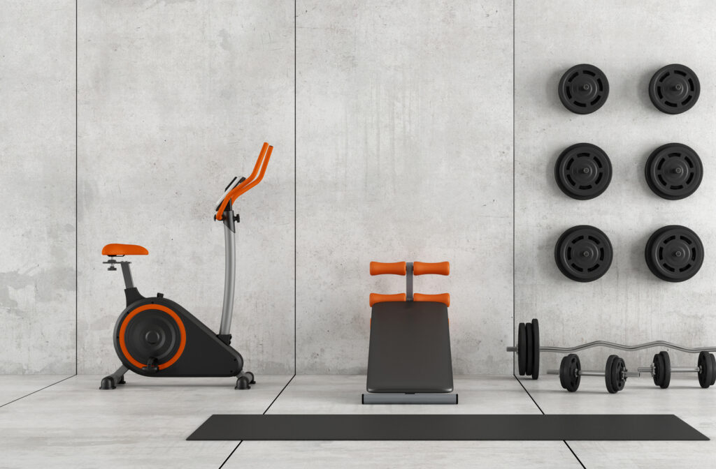 Basement gym with concrete walls and floors featuring exercise bike, sit-up bench, barbell, dumbbells, and wall-mounted plates