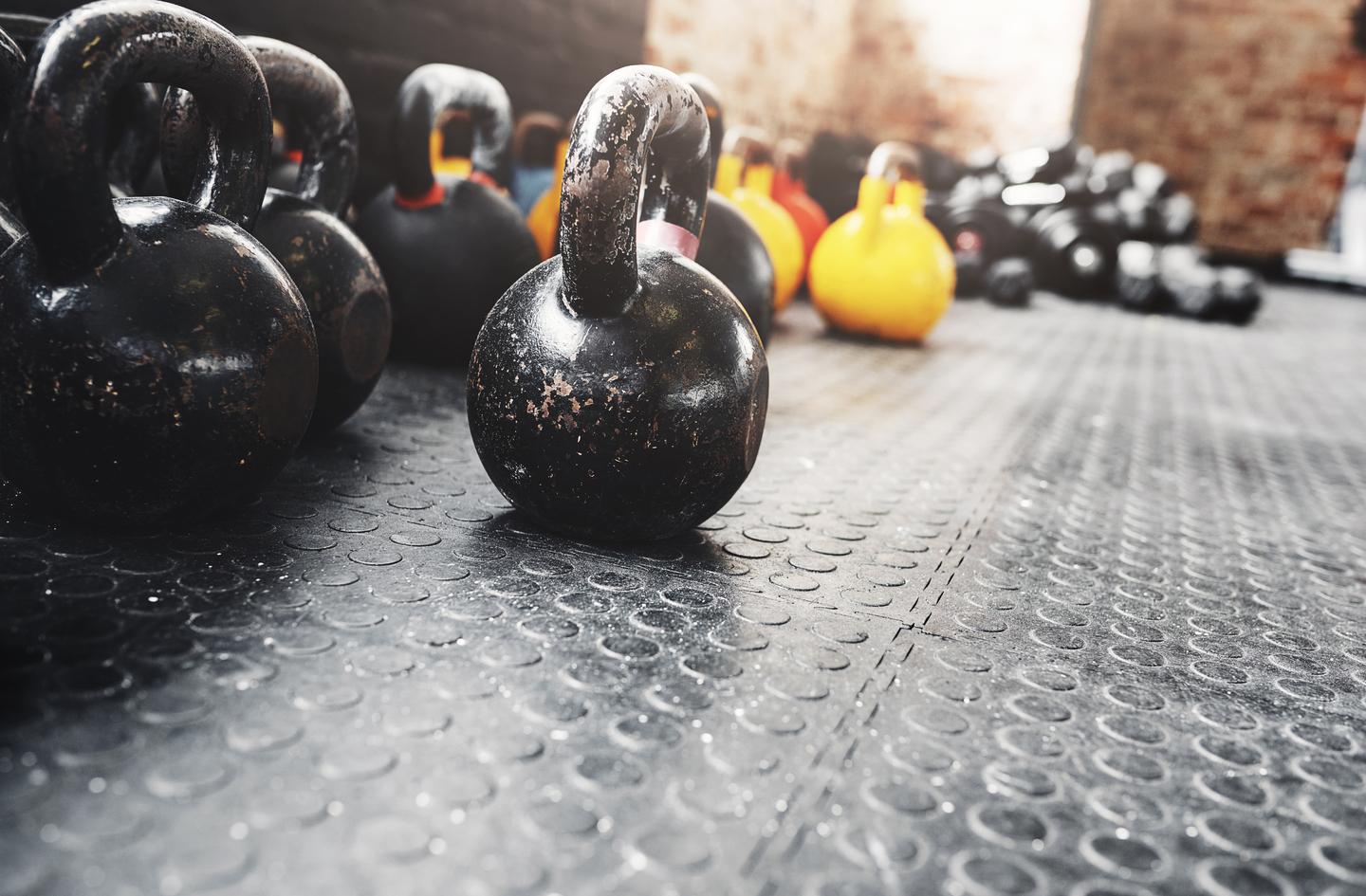 Kettlebells resting on textured rubber gym flooring, showing the surface material used in a basement gym setting