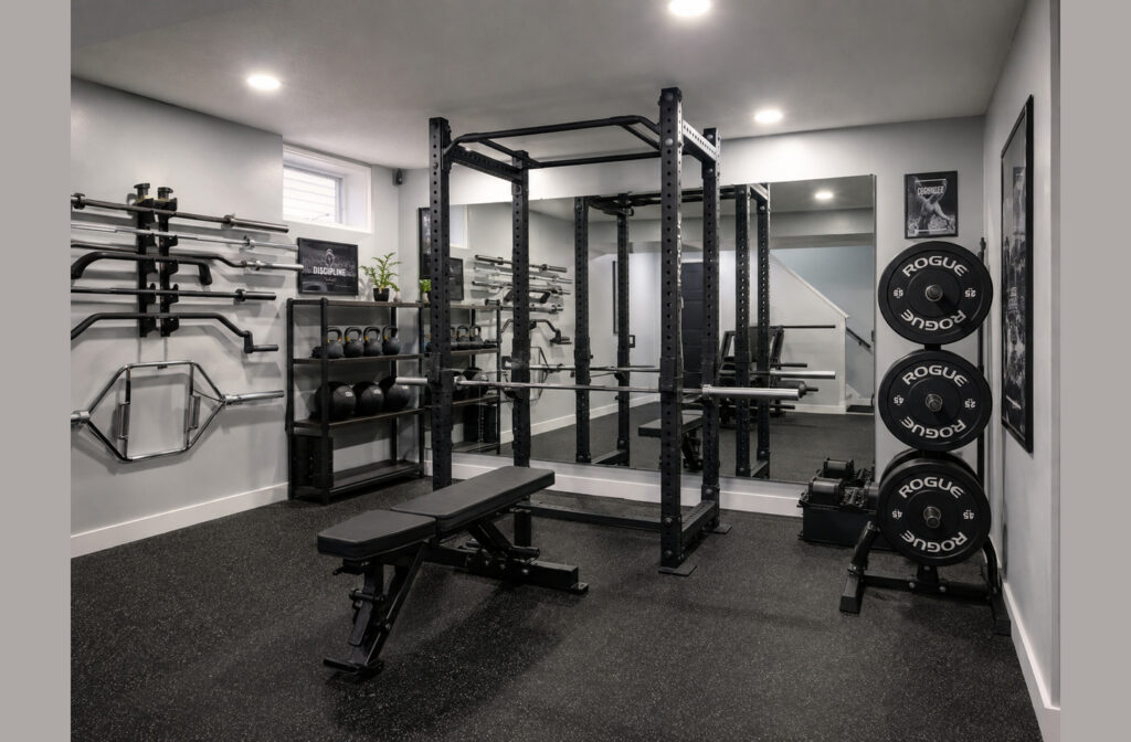 12x12 home gym layout with a central power rack, adjustable bench, vertical plate storage, and wall-mounted barbell racks