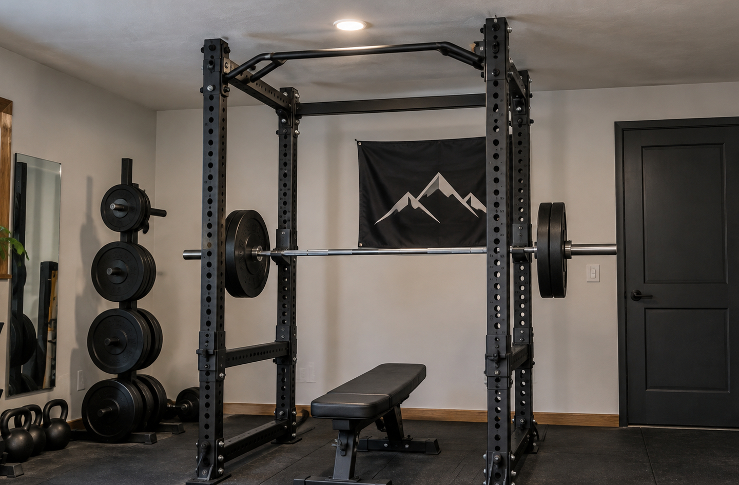 A black metal power rack in a home gym showing the vertical overhead clearance between the pull-up bar and the ceiling, with a loaded barbell, a weight bench, and a plate tree